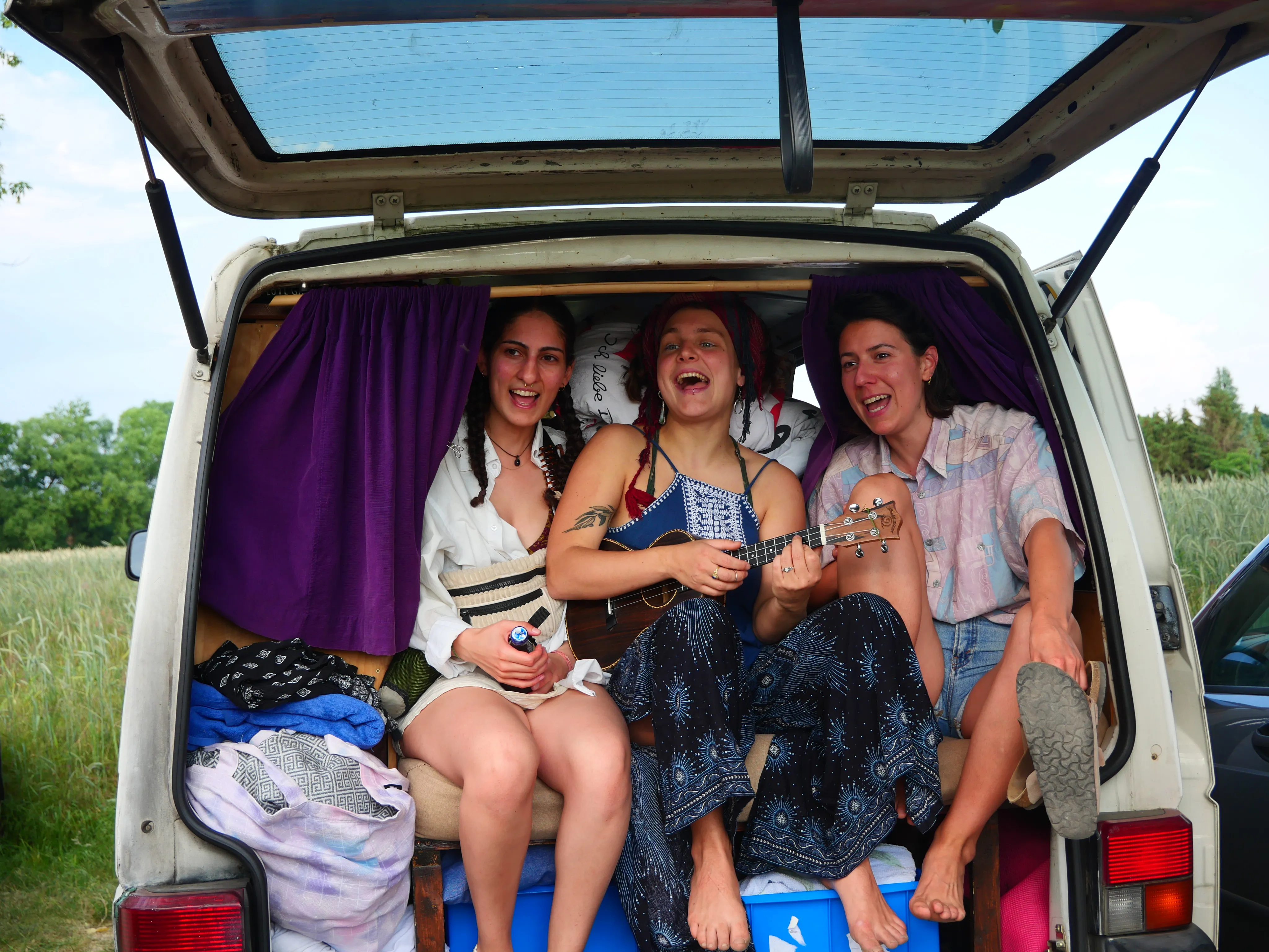 Menschen sitzen in einem Van und singen. Die Person in der Mitte spielt Ukulele.